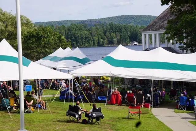 Crowd at the Adirondack Folk Music Festival in Schroon Lake Town Park with lake and mountains