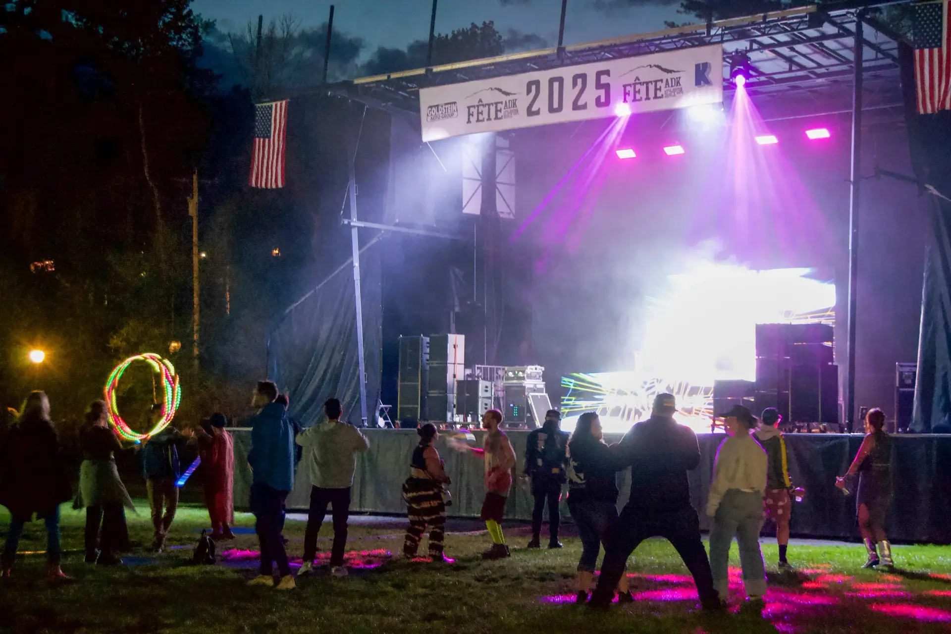 DJ performing on stage at FETE ADK festival in Lake George NY with crowd and LED lights