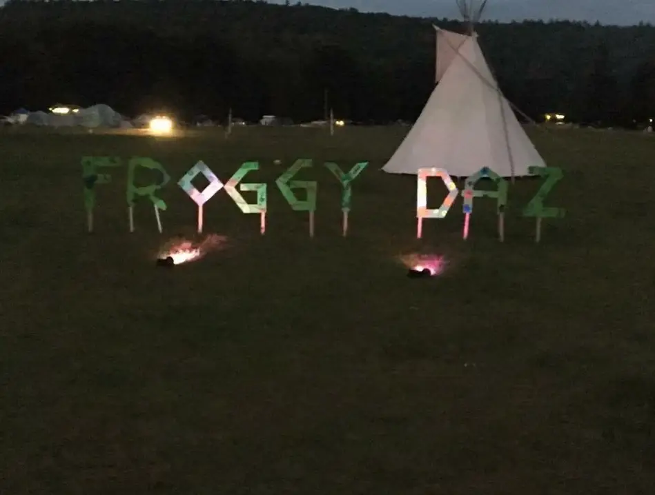 Froggy Daze festival sign lit up at dusk with a tipi in Narrowsburg NY