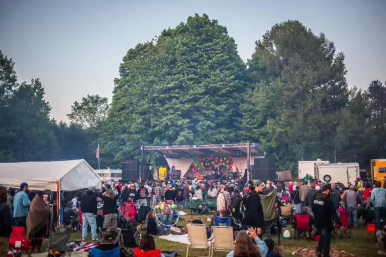 Festival crowd at Sterling Stage Kampitheater with band performing on wooded outdoor stage