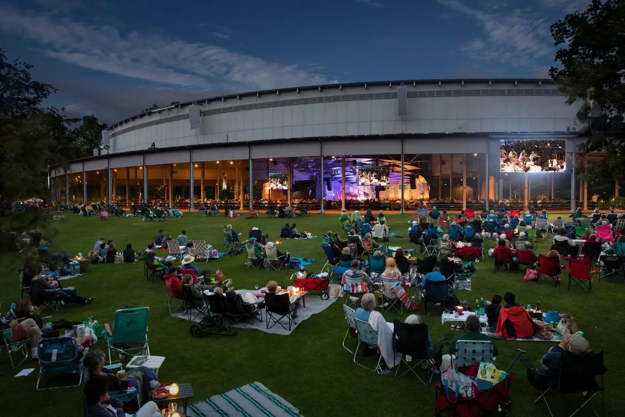 The Koussevitzky Music Shed exterior at night showing the open-air roof structure and lawn audience at Tanglewood