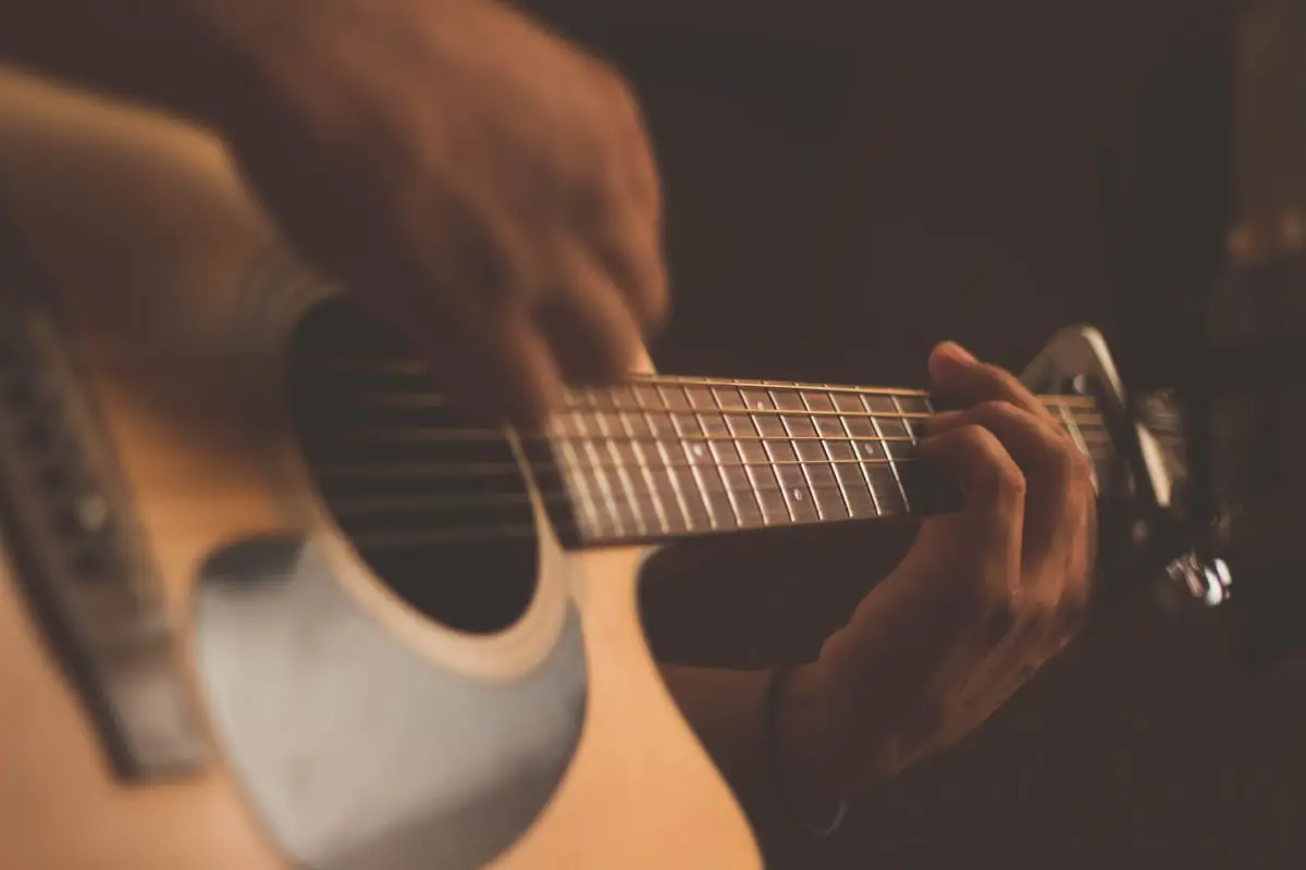 Musician strumming acoustic guitar with capo