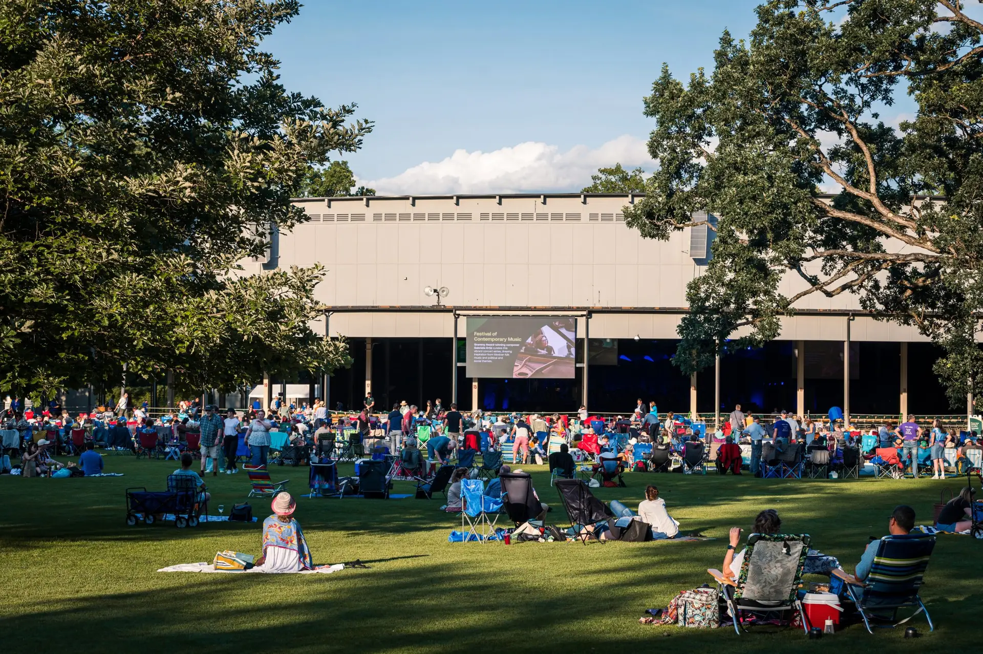 Wide shot of Tanglewood lawn during a summer concert with concertgoers on blankets and the Koussevitzky Music Shed in the background