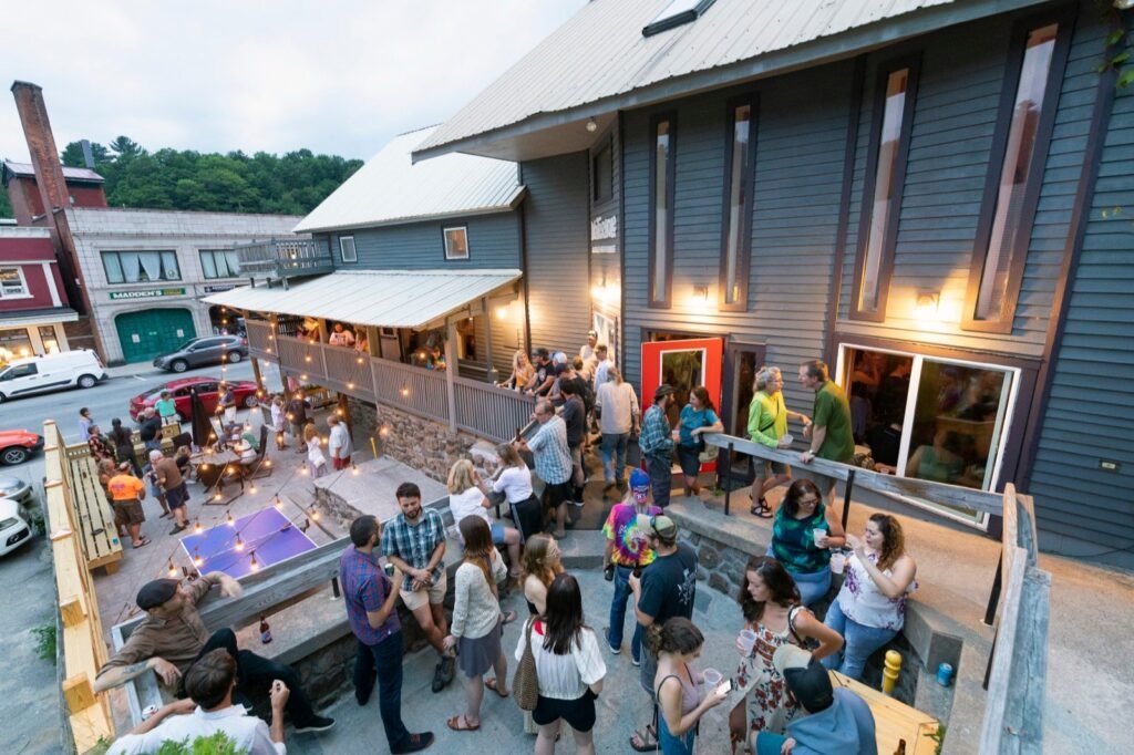 The Waterhole Music Lounge outdoor patio with ping pong table and tiered seating in Downtown Saranac Lake