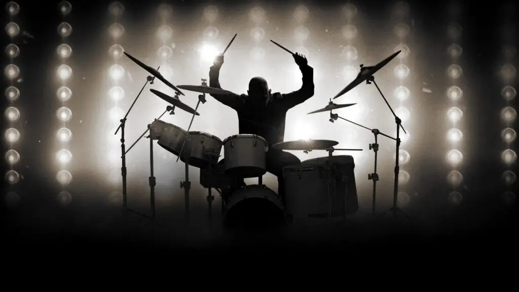 The Phil Collins Story performs live — drummer silhouette with raised drumsticks under dramatic stage spotlights