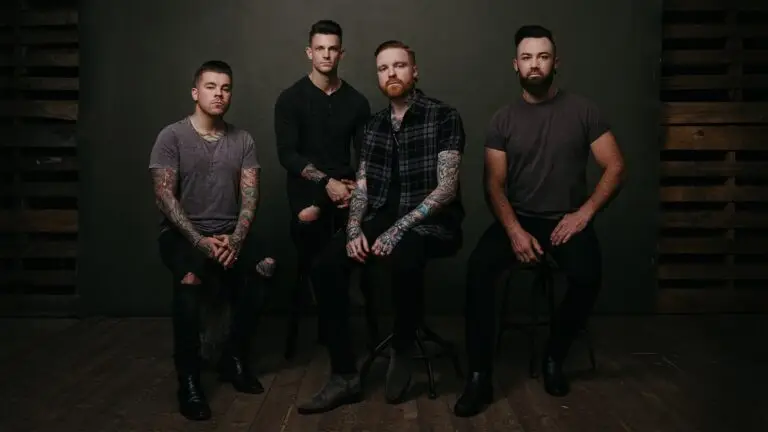 Memphis May Fire band promo photo — four members seated in a moody studio setting