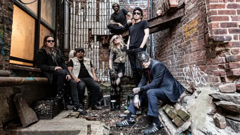 Leftöver Crack band promotional photo — six members posed in urban alleyway with brick walls and graffiti