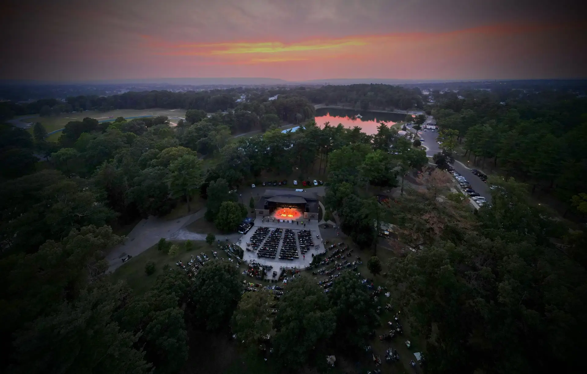 Aerial drone view of the Agnes Macdonald Music Haven Stage bandshell and Central Park grounds in Schenectady, New York, during a summer Sunday concert
