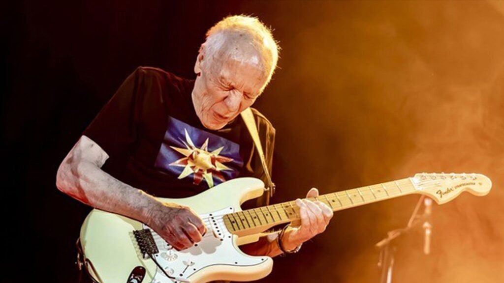 Robin Trower plays his cream Fender Stratocaster under warm stage lights during a live performance