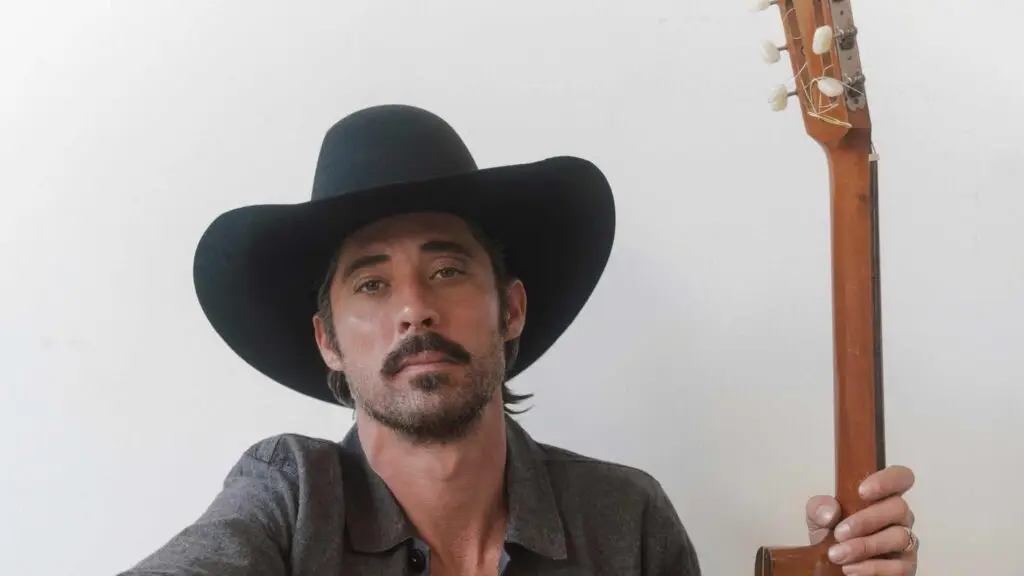 Ryan Bingham in black cowboy hat holding guitar, promotional photo for Artpark Mainstage Theater show