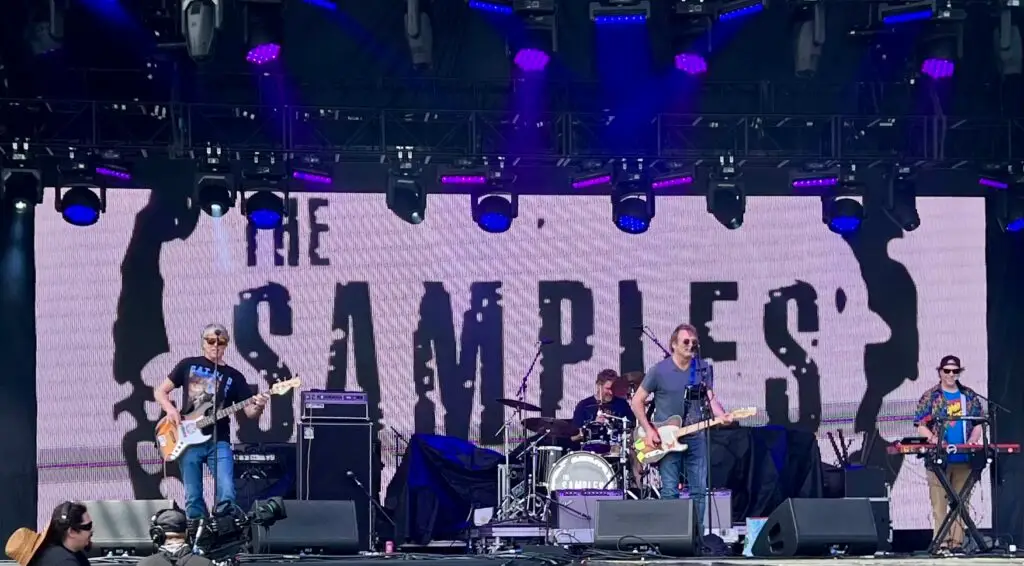The Samples perform live on a festival stage with the band's name lit up on the LED backdrop