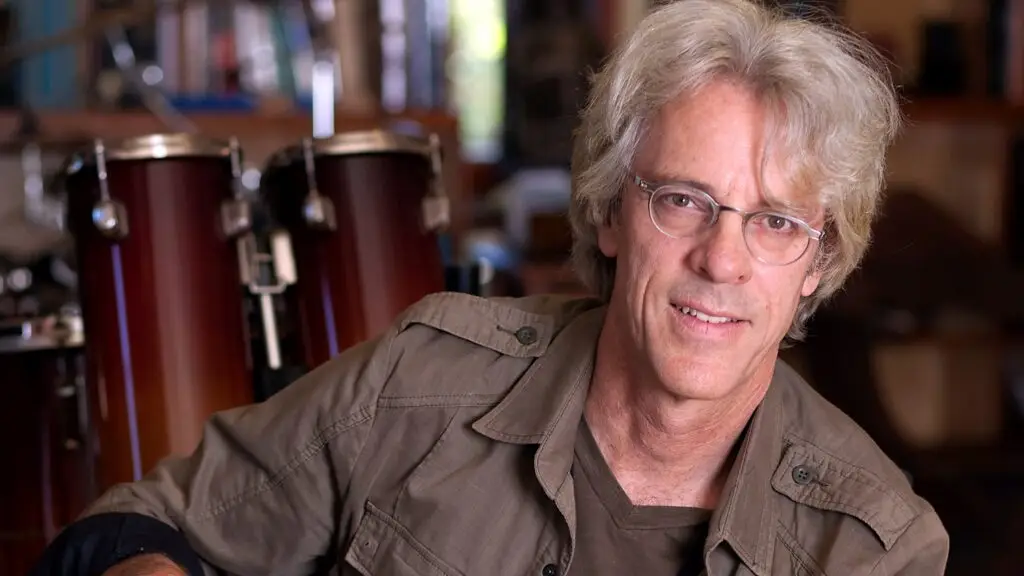 Stewart Copeland seated in front of percussion instruments, official press photo