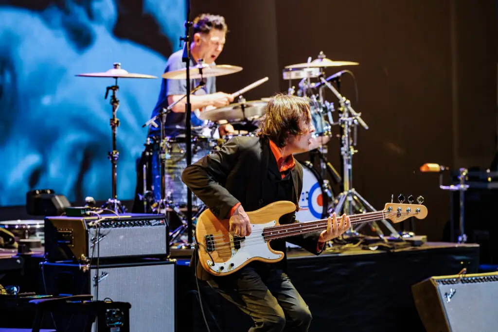 The Sixties Show performers on stage — bassist and drummer with 60s-themed production