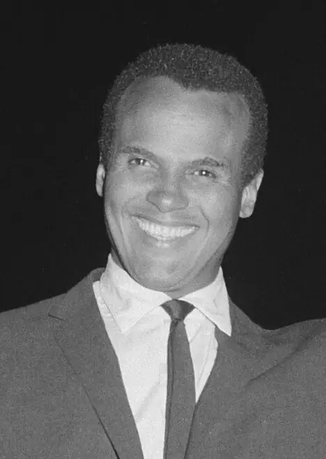 Black-and-white photograph of Harry Belafonte in a dark suit and tie, smiling, May 1964.