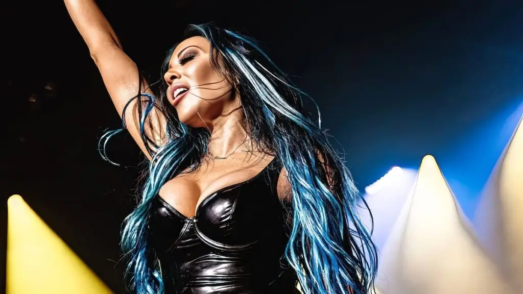 Lords of Acid vocalist Carla Harvey performing on stage with blue and yellow stage lighting