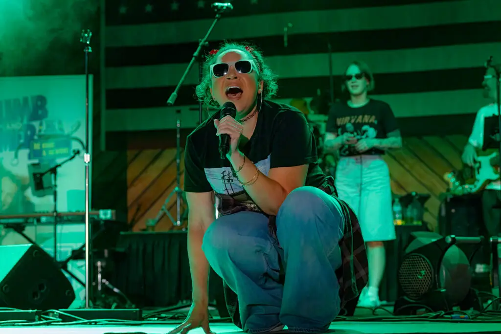 Be Kind and Rewind vocalist performing live on stage with microphone at summer outdoor concert