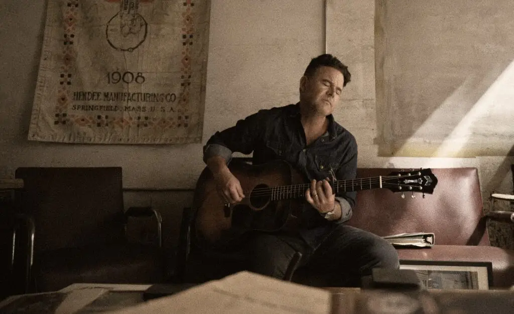 David Nail playing acoustic guitar in an intimate indoor setting, press photo for 2026 Down to the Studs Tour