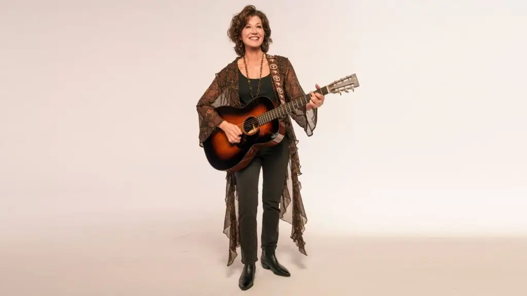 Amy Grant with acoustic guitar, promotional press photo for The Me That Remains tour 2026
