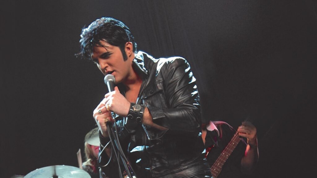 Ryan Pelton performing live in black leather Elvis tribute show on stage with microphone