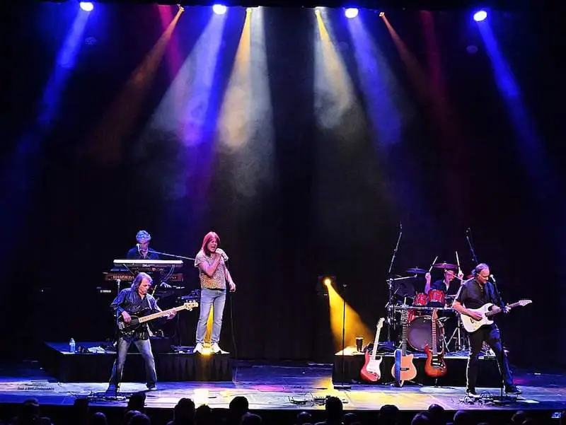 Grand Evolution tribute band performing live on stage with colorful stage lighting