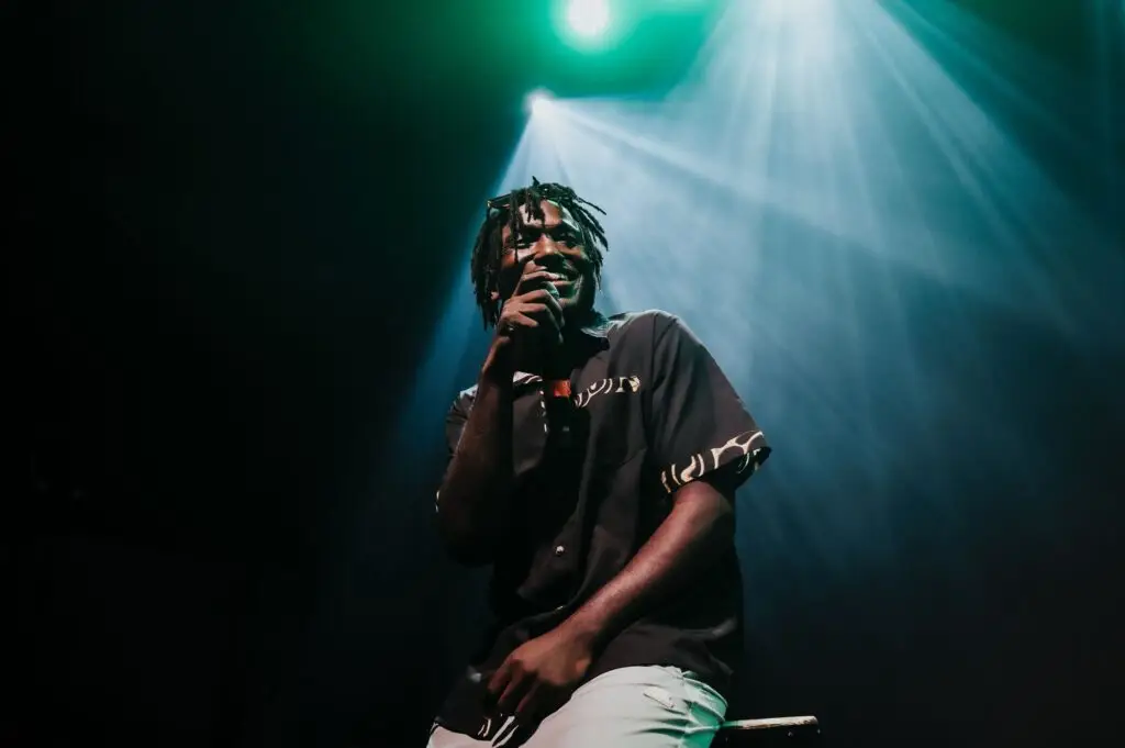 Hannibal Buress performing stand-up live on stage under teal stage lighting