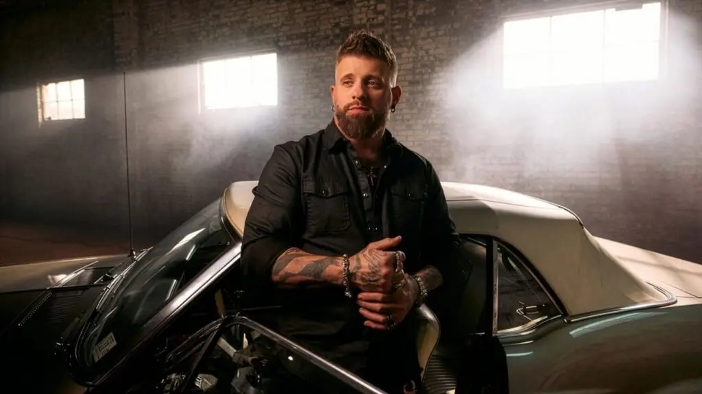 Brantley Gilbert official 2026 promotional portrait, tattooed country-rock artist posed with classic muscle car