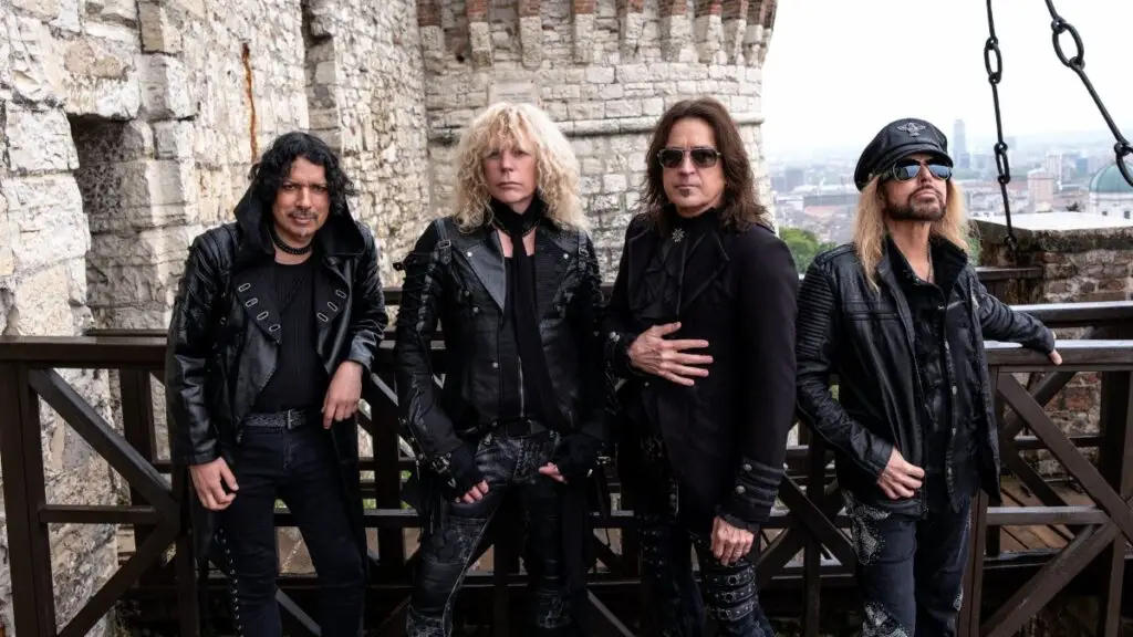 Stryper band photo, four members in black leather posed at a stone fortress for their 2026 Four Decades tour