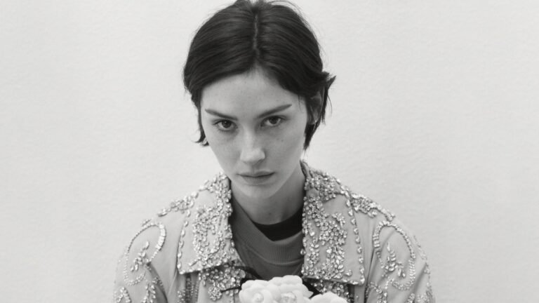 Gracie Abrams in official press photo, black-and-white portrait in jewel-embellished jacket