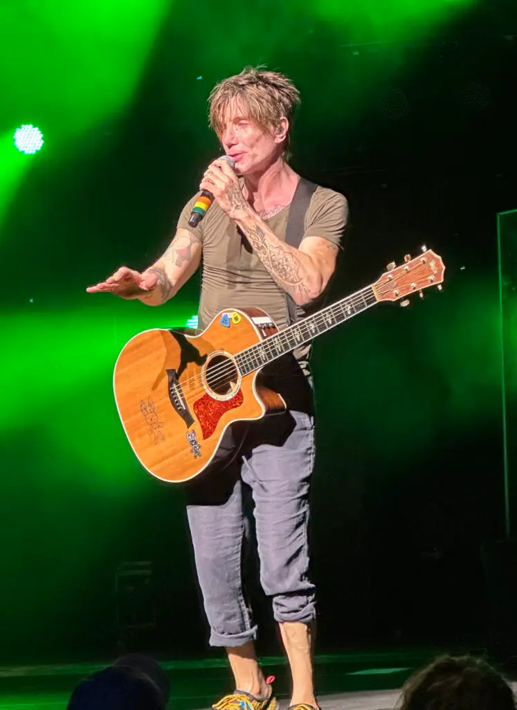 John Rzeznik of the Goo Goo Dolls singing with an acoustic guitar under green stage light
