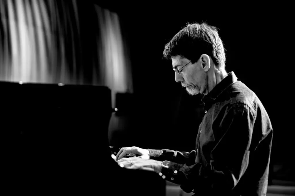 Fred Hersch playing grand piano in concert, black-and-white profile