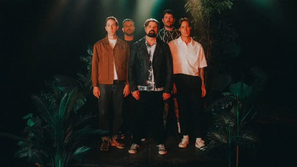 Silverstein five-piece band official press photo in dark studio with tropical plants backdrop