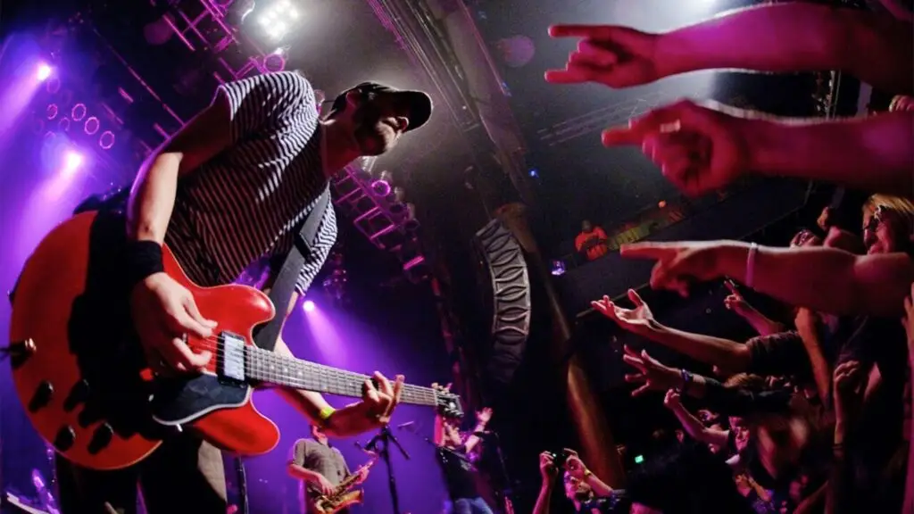 Streetlight Manifesto guitarist performing live, red electric guitar, crowd reaching toward stage