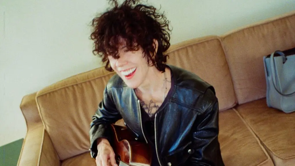 LP performing acoustic guitar, smiling, in black leather jacket — All Is Not Lost Tour 2026