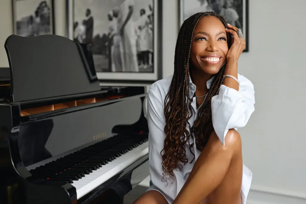 Heather Headley seated beside a grand piano, press photo for her Mahaiwe Performing Arts Center concert