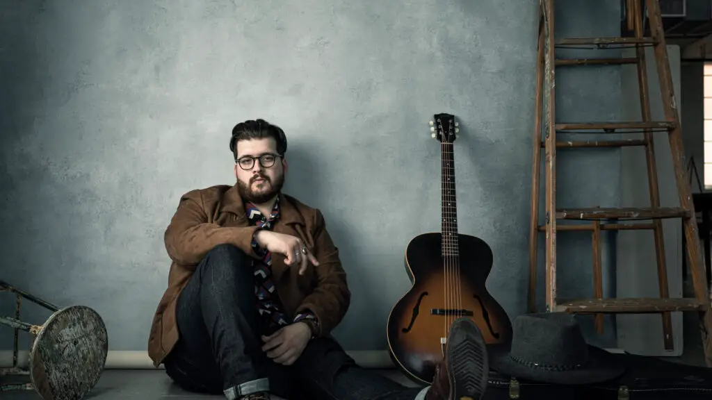 Noah Guthrie seated with archtop guitar in studio press photo