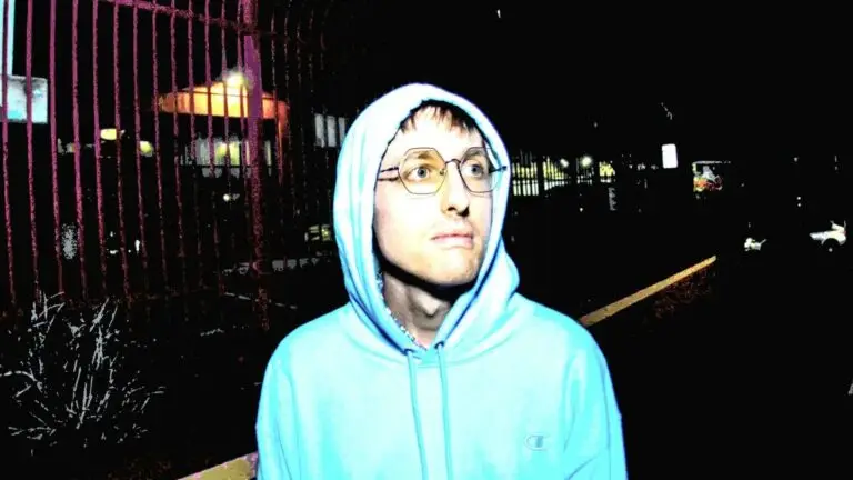 Yheti (Tyler Holler) in a light blue hoodie at night, urban street setting
