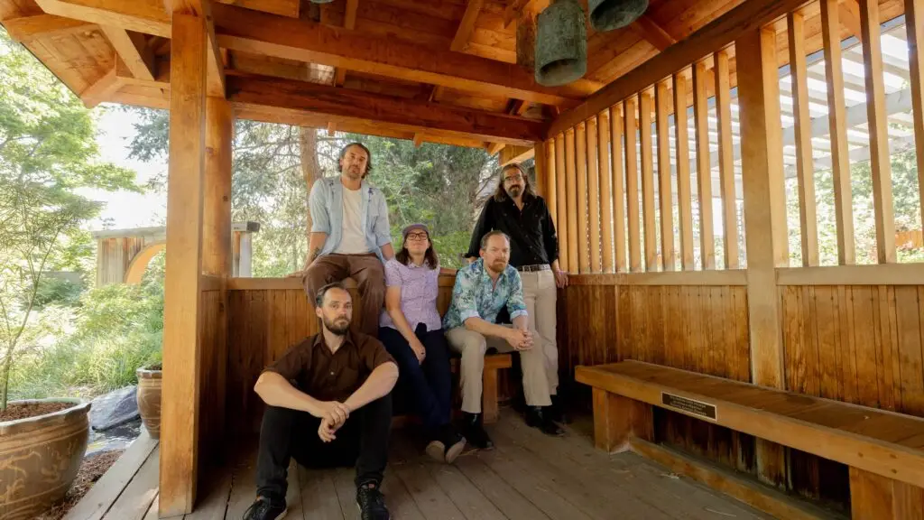 Fruition, five-piece Portland Americana band, press photo in a wooden garden pavilion