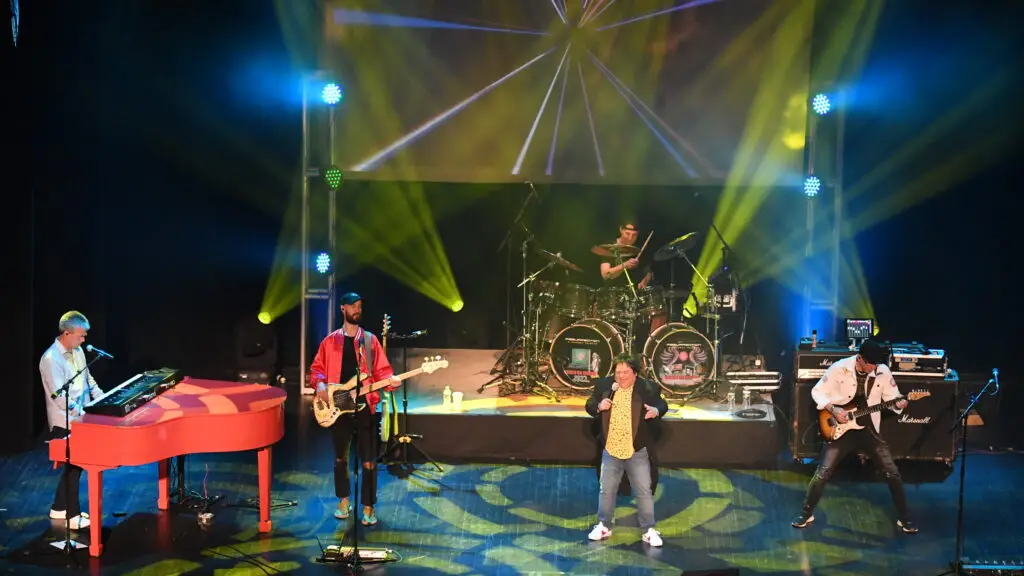 Resurrection: A Journey Tribute performing live on stage with red baby grand piano and dramatic beam lighting