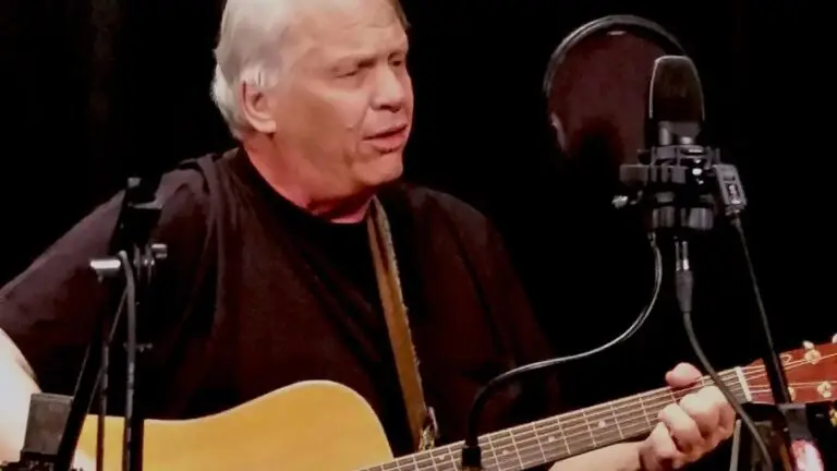 Barry 'The Fish' Melton performing live, playing acoustic guitar at a microphone on stage