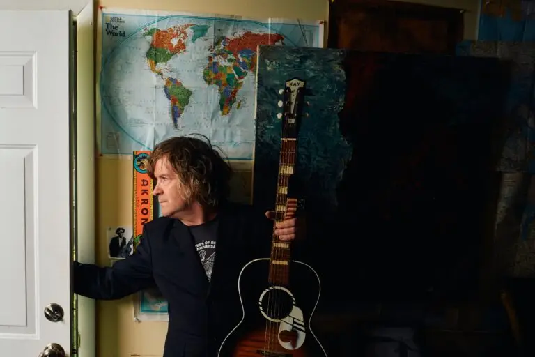 Tim Easton holding a vintage Kay acoustic guitar in a studio doorway
