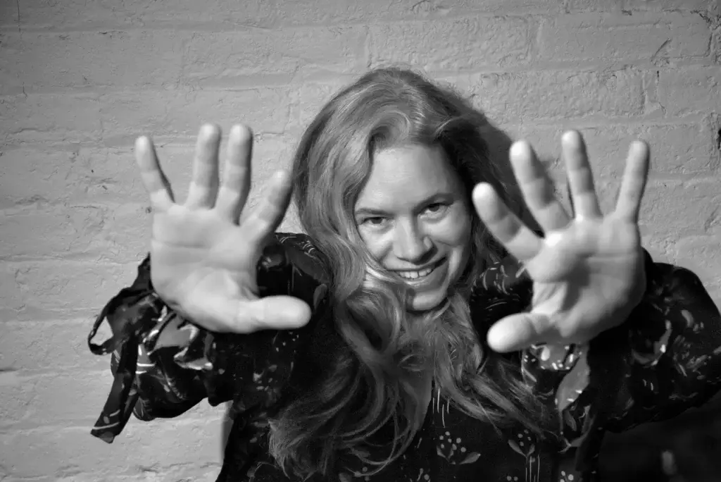 Natalie Merchant in official press photo by Shervin Lainez, smiling with hands outstretched