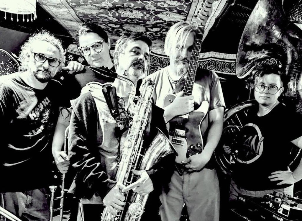 Eight Foot Manchild band members with tuba, trombone, saxophone, and guitar in B&W press photo