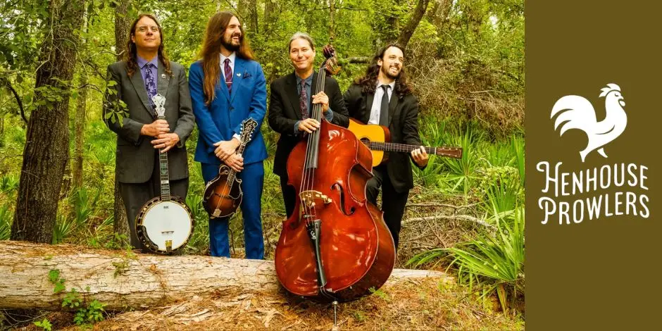 Henhouse Prowlers quartet posing with banjo, mandolin, upright bass, and guitar in an outdoor forest setting