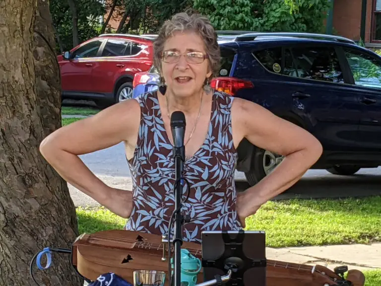 Deb Cavanaugh performs outdoors at a mic stand with her mountain dulcimer