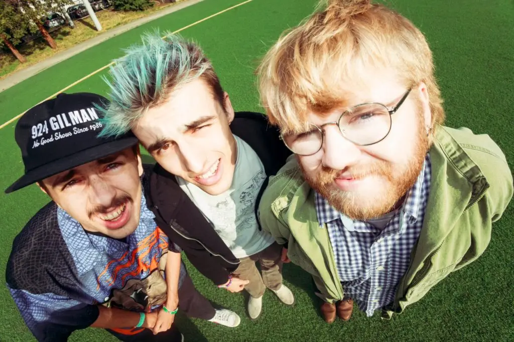 Aren't We Amphibians, San Diego emo trio, photographed from above on a green turf field
