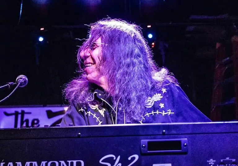 Bruce Katz performing live at Hammond keyboard, long wavy hair, smiling, purple stage lighting