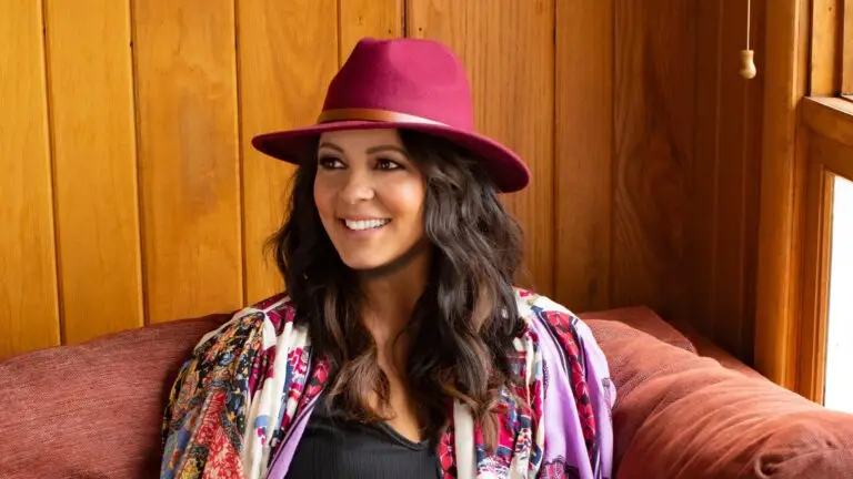 Sara Evans performing country music, smiling in burgundy hat and floral jacket
