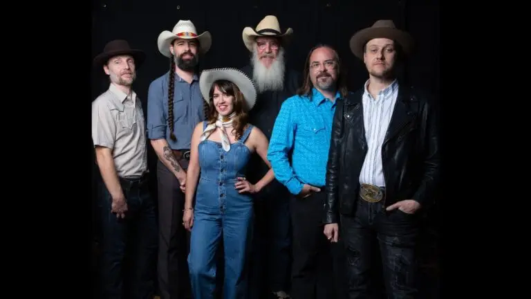Asleep at the Wheel six-piece band studio press photo, members in cowboy hats and western attire, black backdrop