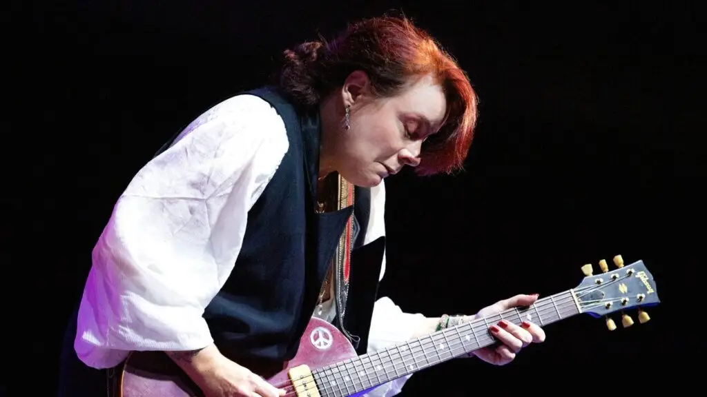 Carolyn Wonderland performs live, playing purple Gibson Les Paul guitar on a darkened stage