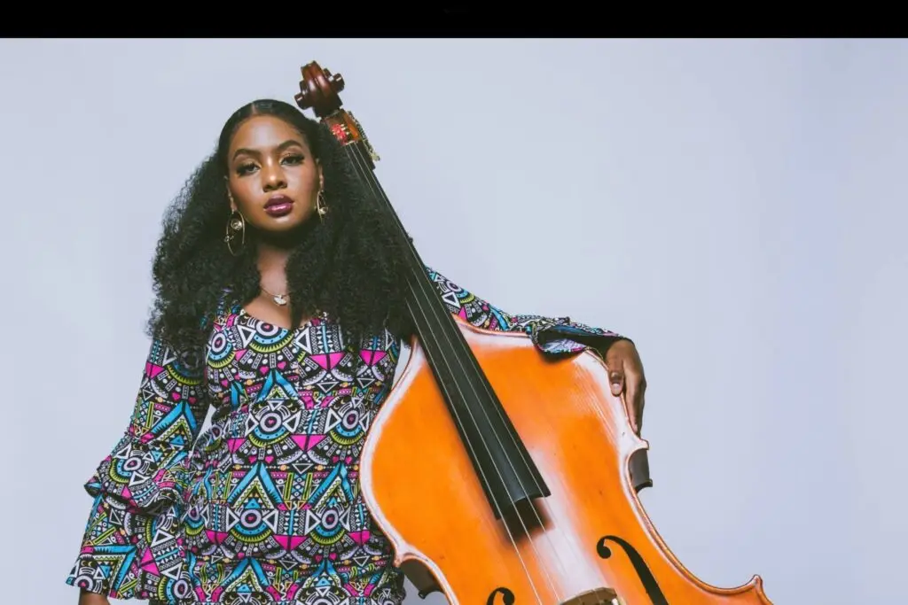 Endea Owens with her upright bass, wearing a colorful patterned dress, press photo